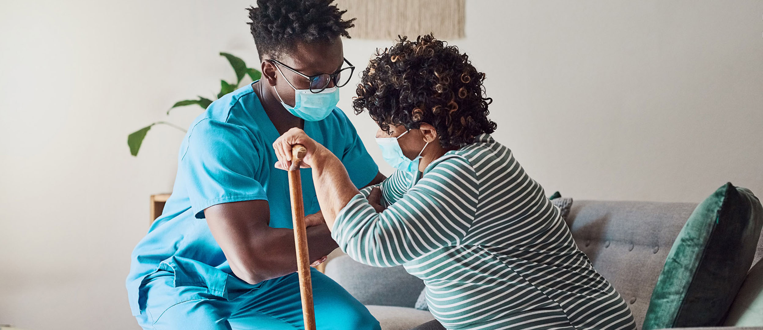 Nurse assisting elderly woman to stand with a cane Nurse assisting elderly woman to stand with a cane